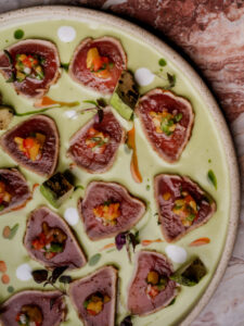 L&iacute;o Mykonos: One Last Spectacularrr Night. An overhead view of a carefully arranged dish with green sauce and small garnishes.