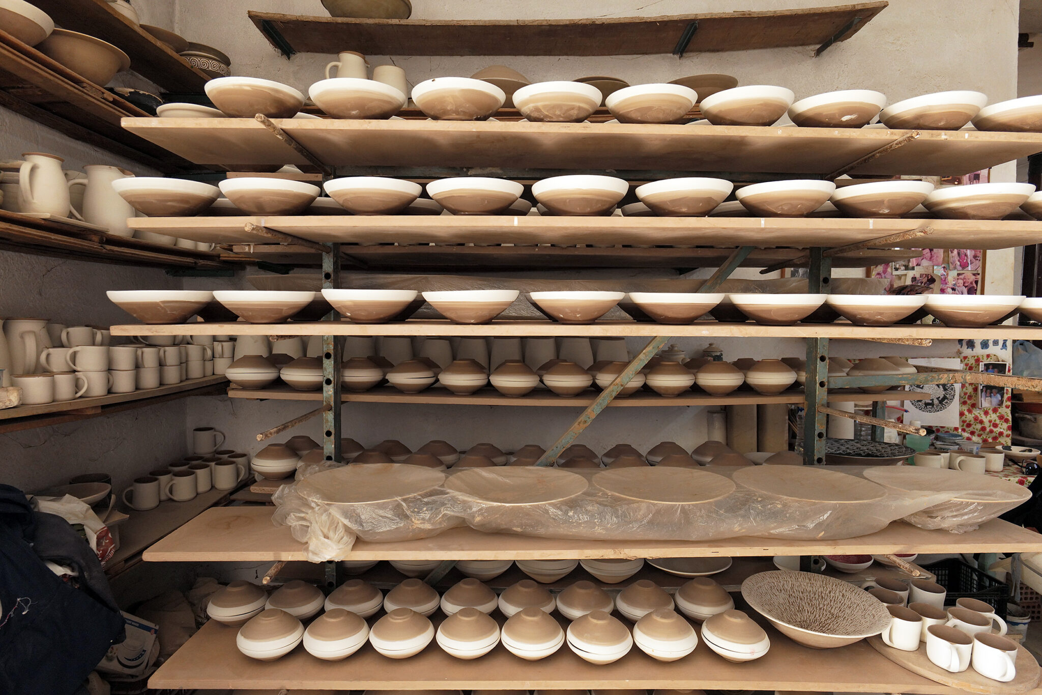 Inside the Pottery Workshops of Sifnos: rows of ceramic vessels on shelves at the Lebesis workshop