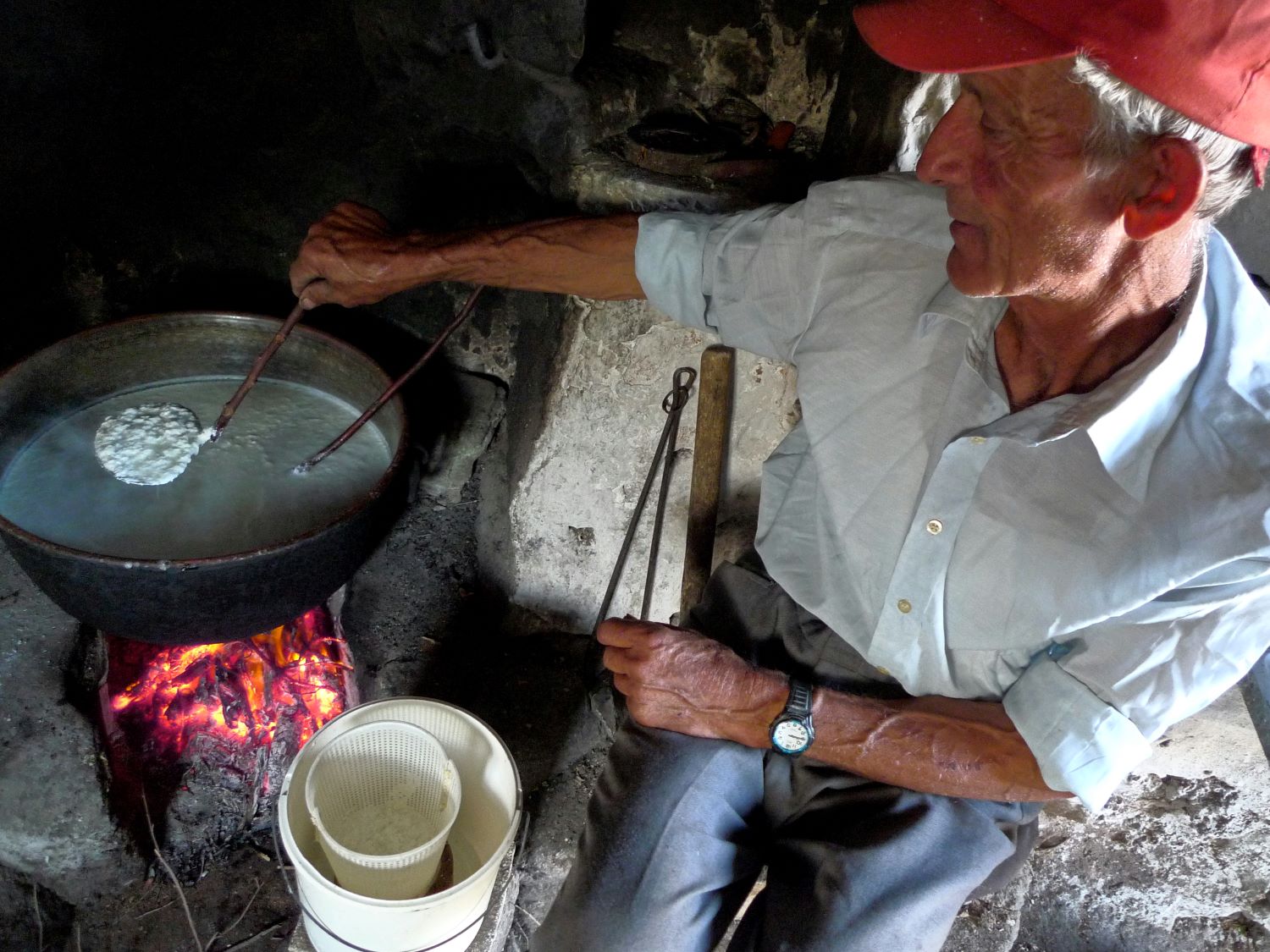 Cheeses of the South Aegean: A cheesemaker tending a cauldron in a Folegandros farmhouse