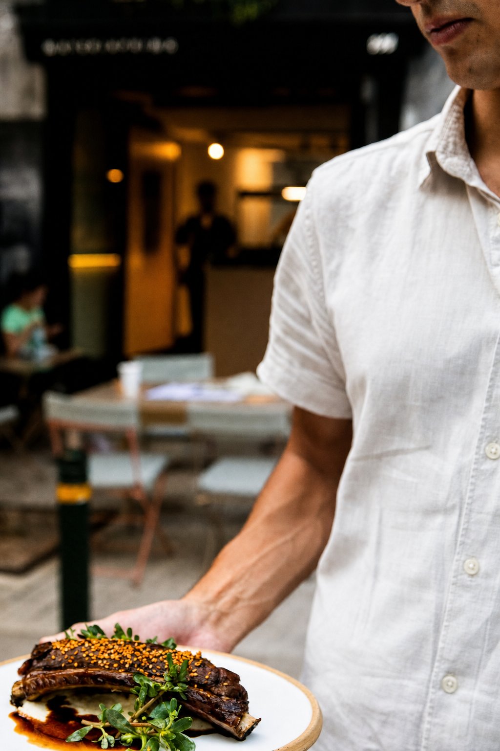 Koukaki&rsquo;s Best Places to Eat: Materia Prima, a server carrying a plated dish