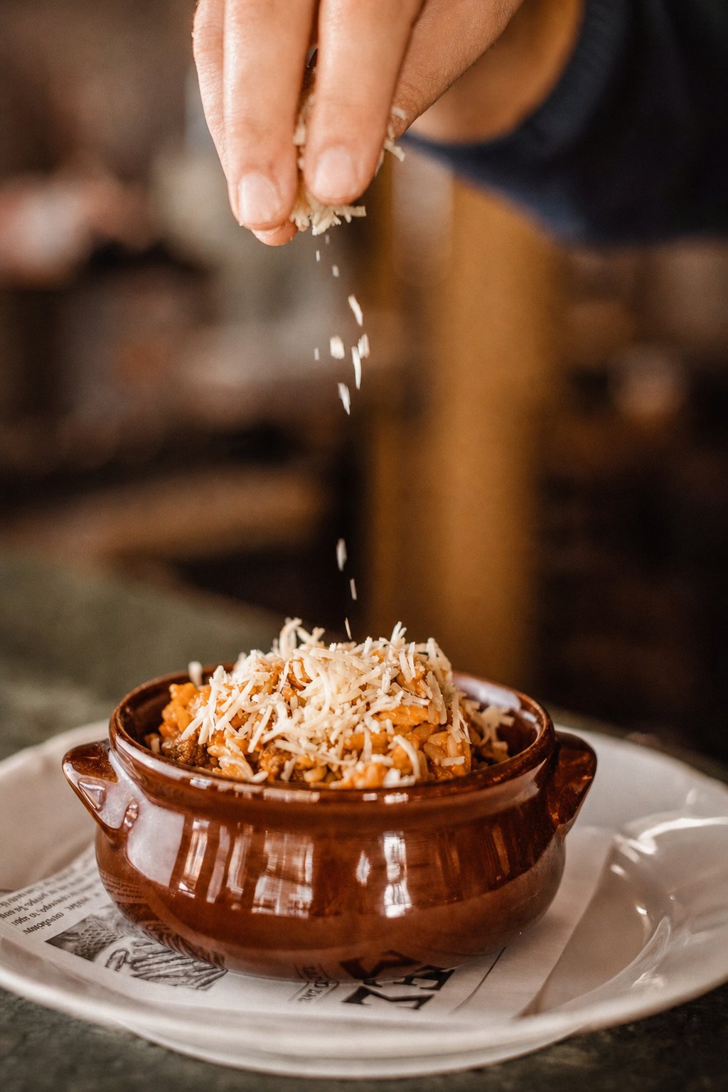 Koukaki&rsquo;s Best Places to Eat: Thomas 1971, grated cheese being sprinkled over a dish in a clay pot