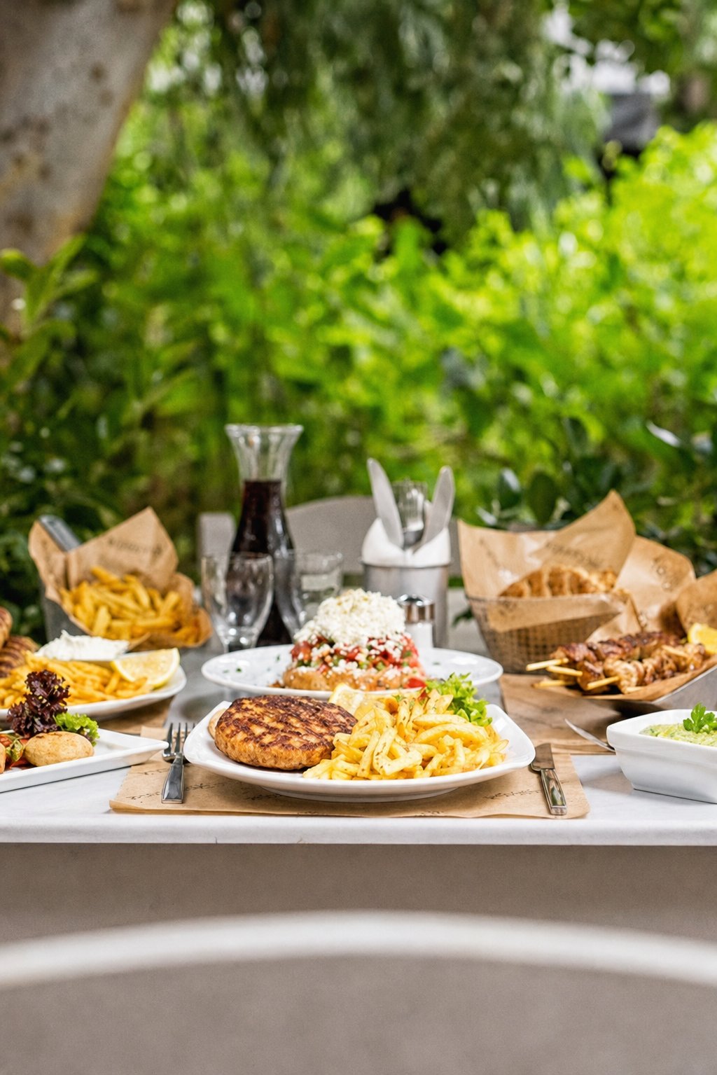 Koukaki&rsquo;s Best Places to Eat: Kalamaki Bar, a table set with grilled food, fries, and drinks
